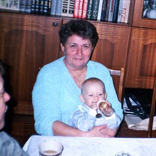 Woman holding baby at a table with family.