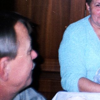 Woman holding baby at a table with family.