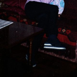 Woman holding baby, seated on a floral couch.