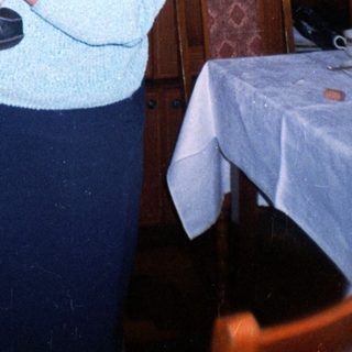 Woman holds baby indoors, standing near furniture and cabinets.