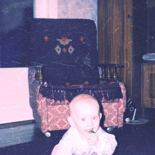 Baby crawls amidst scattered flowers in a vintage room.