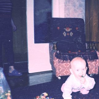 Baby crawls amidst scattered flowers in a vintage room.