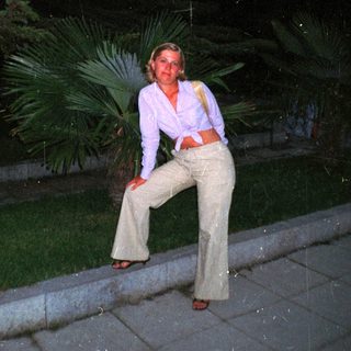 Woman in flared pants poses outdoors at dusk.