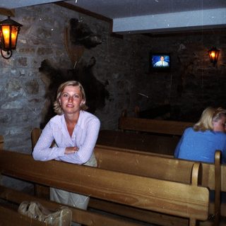 Woman sits in a rustic room with a TV.