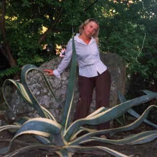 Woman standing near agave plant in a garden.