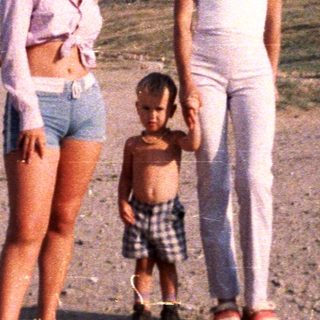 Two women and a child stand near a fortress.