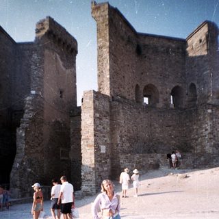 Ruins and people on a sandy area in daylight.