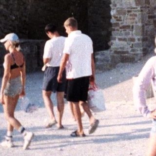 Ruins and people on a sandy area in daylight.