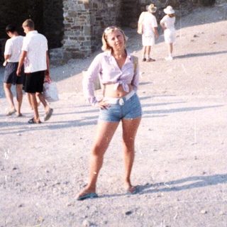 Ruins and people on a sandy area in daylight.