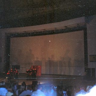 Concert stage with audience visible in a darkened venue.