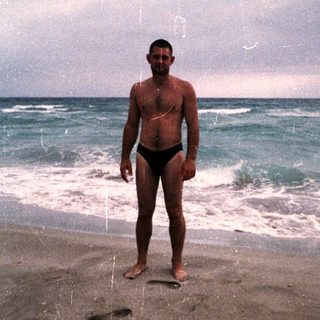 Man stands on a beach with ocean waves behind.