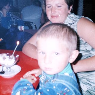 Boy sits on a lap, eating dessert with family.