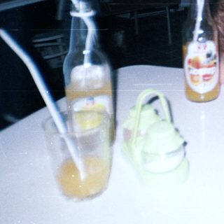 Boy sleeps on table with drinks and people nearby.