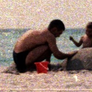 Two people build a sandcastle on a beach.