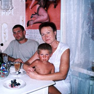 Family seated at a table with drinks and a portrait on wall.