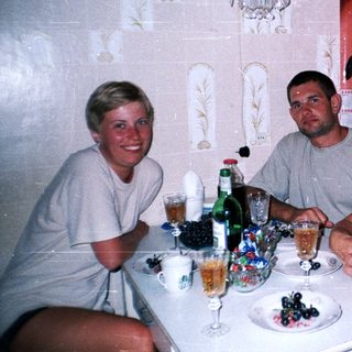 Family seated at a table with drinks and a portrait on wall.