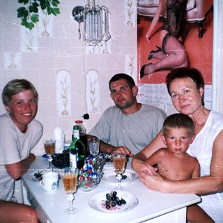 Family seated at a table with drinks and a portrait on wall.