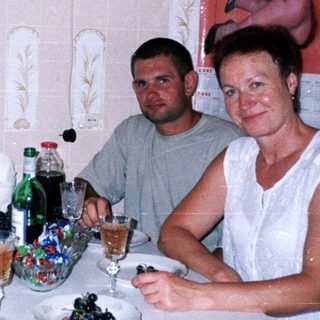 Family seated at table with drinks and fruit.