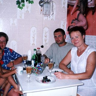Family seated at table with drinks and fruit.