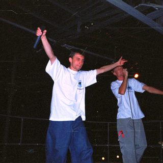 Two men perform on stage, appearing to rap or speak.