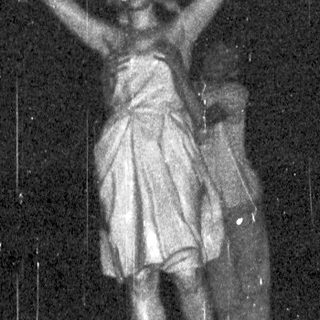 Statue of a woman holding a lamp stands illuminated.