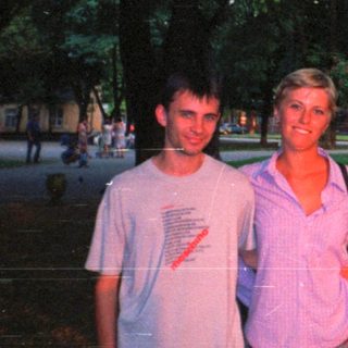 Couple posing outdoors in a park-like setting.