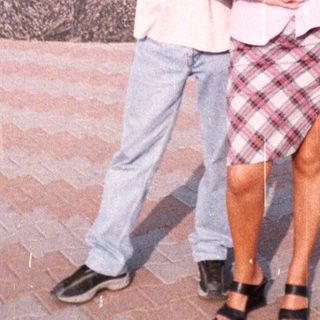 Couple poses near a statue and building outdoors.