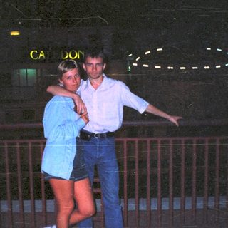 Couple posing at night with a building in the background.