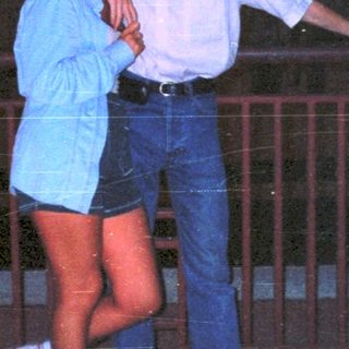 Couple posing at night with a building in the background.