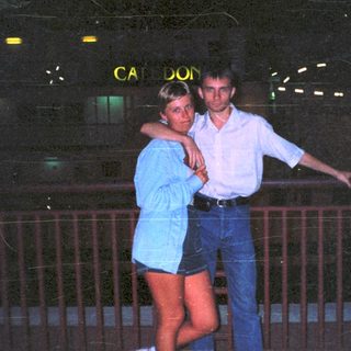 Couple posing at night with a building in the background.
