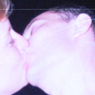 Couple kissing in a dimly lit, nighttime setting.