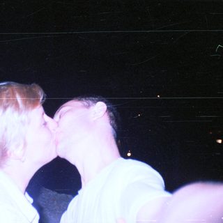Couple kissing in a dimly lit, nighttime setting.