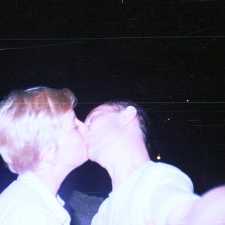 Couple kissing in a dimly lit, nighttime setting.