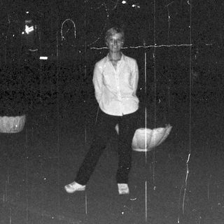 Man stands outdoors at night, blurred background lights visible.