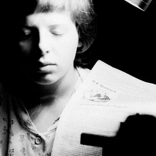 Girl reading a document under a lamp in darkness.