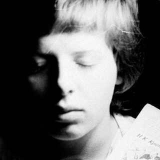 Girl reading a document under a lamp in darkness.