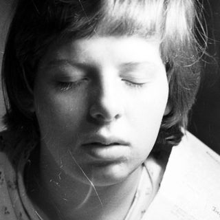 Black and white portrait of a young person with a solemn expression.