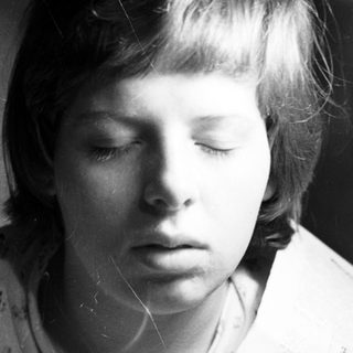 Black and white portrait of a young person with a solemn expression.