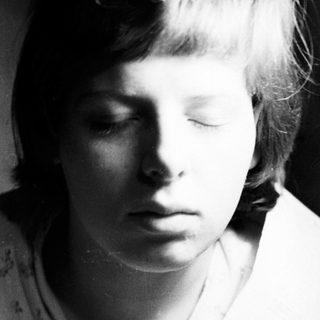 Here's a brief summary of the image: Black and white portrait of a young person with short hair.