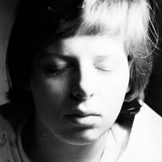 Here's a brief summary of the image: Black and white portrait of a young person with short hair.