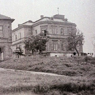 Large, old building sits on a small hill.
