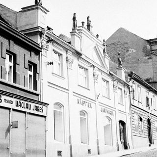Black and white photo of historic buildings along a cobblestone street.