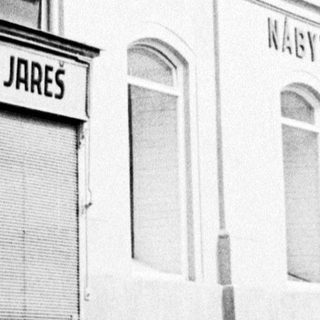 Black and white photo of historic buildings along a cobblestone street.