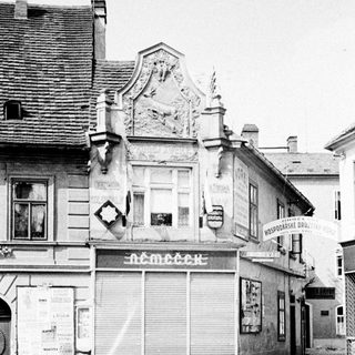 Black and white photo of a building with shuttered storefront.