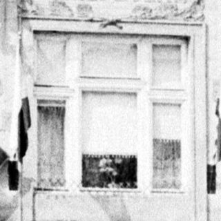 Black and white photo of a building with shuttered storefront.