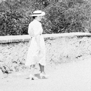 Man and woman walking near a tower and foliage.