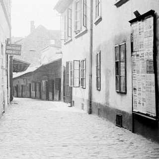 Here's a brief summary of the image: Narrow, cobbled street flanked by tall, old buildings.