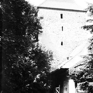 People standing near a stone building with a gate.