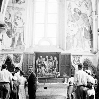 People view a sculpture within an ornate church interior.