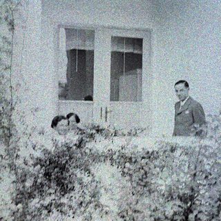 Man and child visible through a window, blurred foliage.